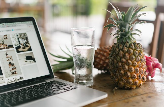 laptop beside glass of water and pineapple