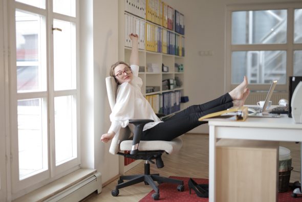 4-Day Workweek Productivity - dreamy female employee relaxing with feet on table in office