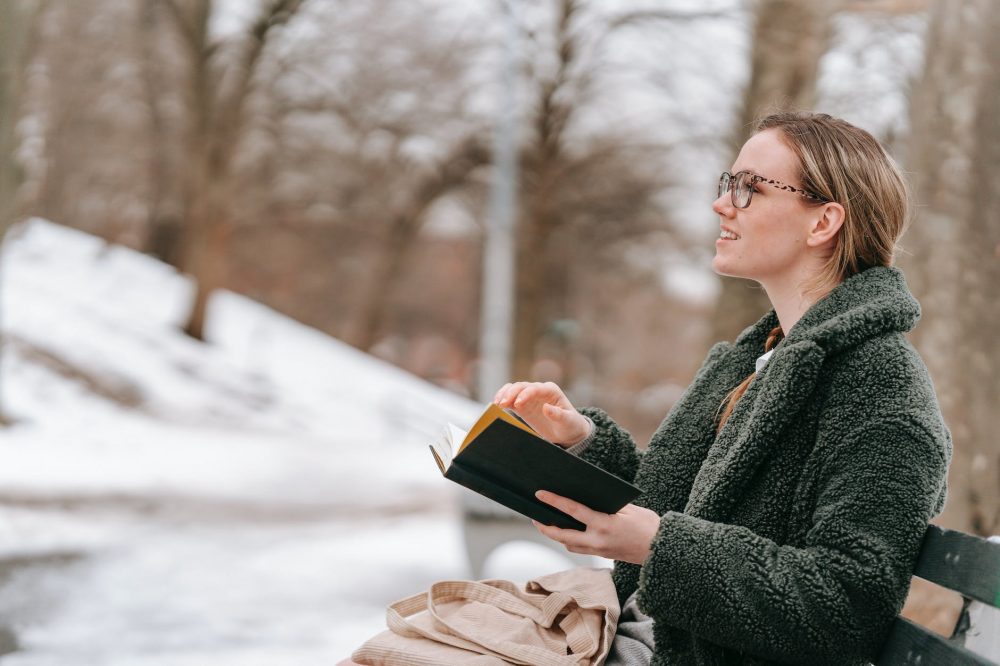 Remote Work im Winter - nutze die Zeit wenn es hell ist und geh raus! - inspired woman with book in winter park